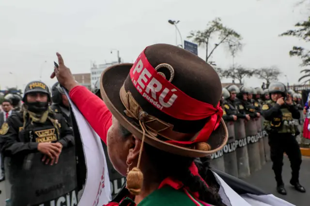 Mulher com chapéu e faixa com nome do Peru em protesto