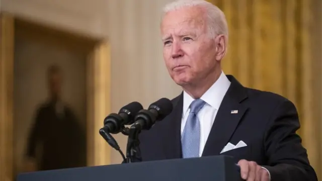 Biden no palanque dentro de sala da Casa Branca