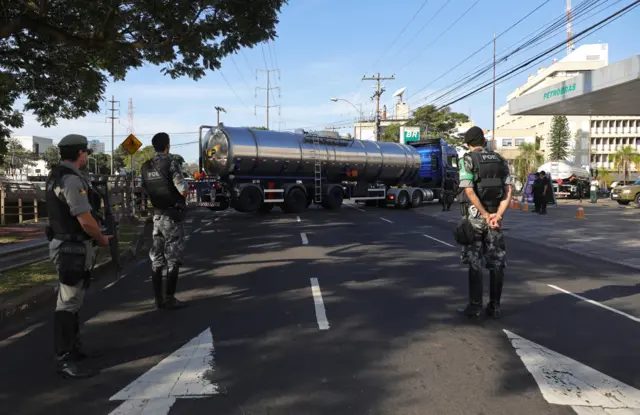 Policiais nas proximidades de posto de combustível