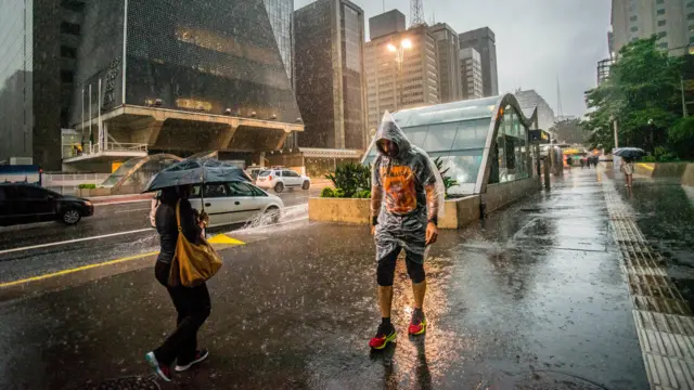 Pessoas andam na chuva em São Paulo