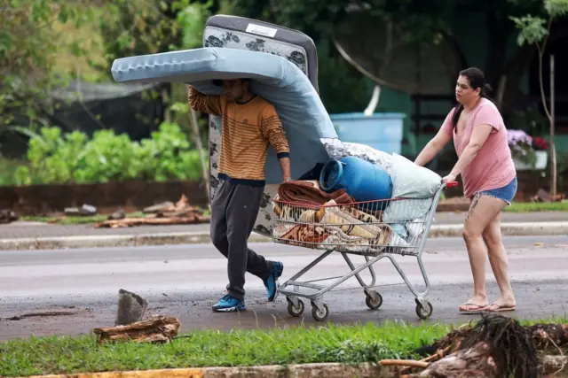 Foto mostra casal levando pertences em um carrinho 