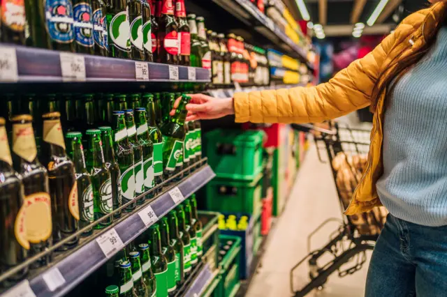 Mulher escolhendo cerveja no mercado