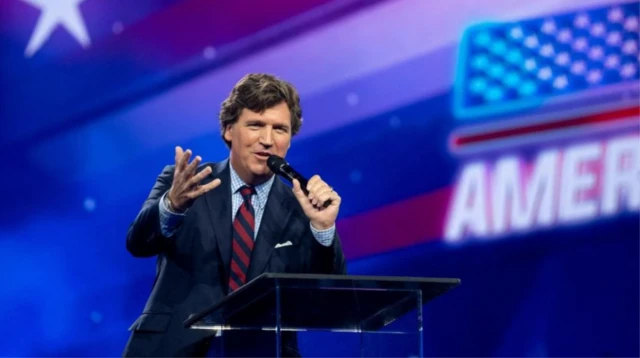 Tucker Carlson gesticulando enquanto fala no microfone