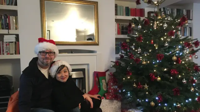 Charles e Julia Reeves, vestindo gorros de Papai Noel, ao lado de uma árvore de Natal, em foto do arquivo da família