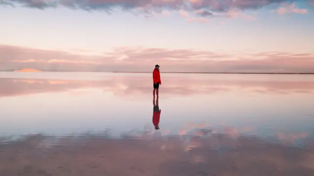 Uma única pessoa parada no meio de uma praia