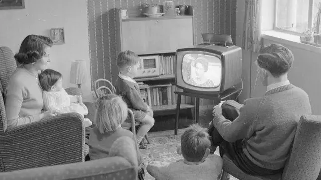 Foto antiga de família vendo TV