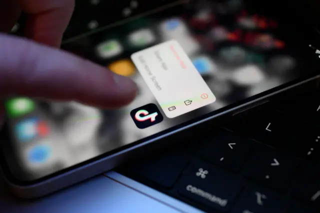 Dedo tocando em aplicativo do TikTok em celular