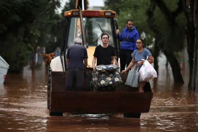 Pessoas sendo resgatas de trator em meio à enchente