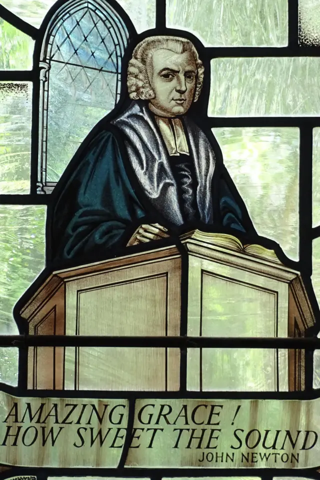 Vitral em igreja com imagem de John Newton e um trecho da música: 'Amazing Grace! How sweet the sound'