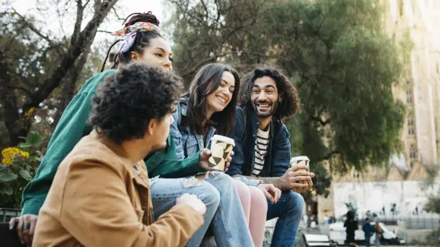 Grupo de jovens toma café em uma praça