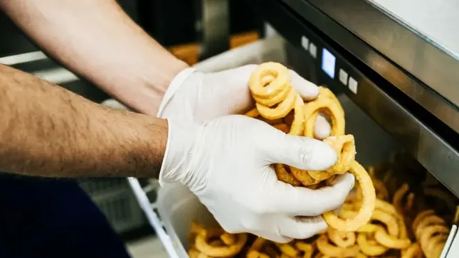 Trabalhador fritando cebolas