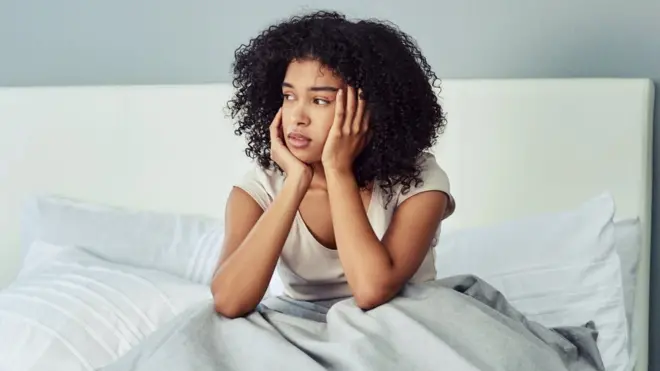 Woman in bed with hands on her cheeks