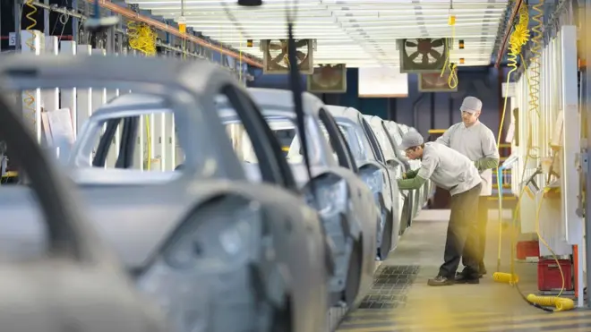 Dois funcionários trabalhando em fábrica de automóvel