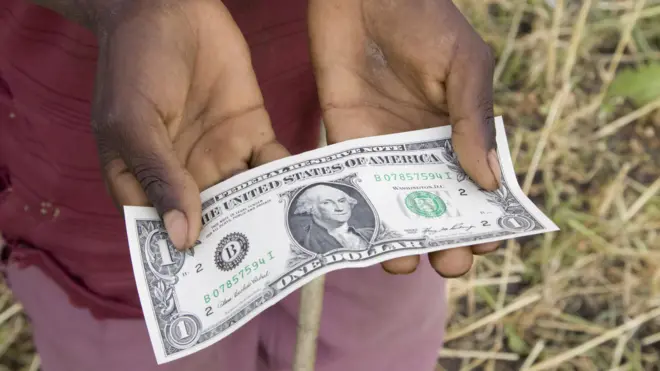Mneino segurando nota de dólar