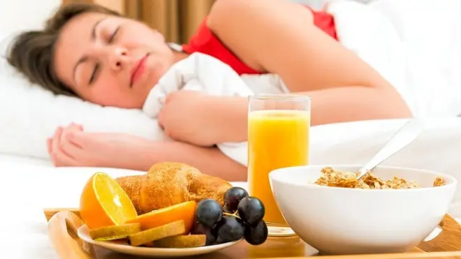 Mujer durmiendo frente a una bandeja de desayuno