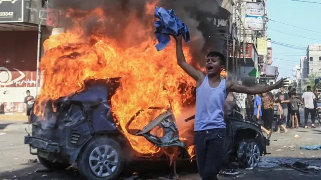 Um menino palestino reage diante de um carro israelense em chamas apreendido por militantes e levado para Gaza no sábado