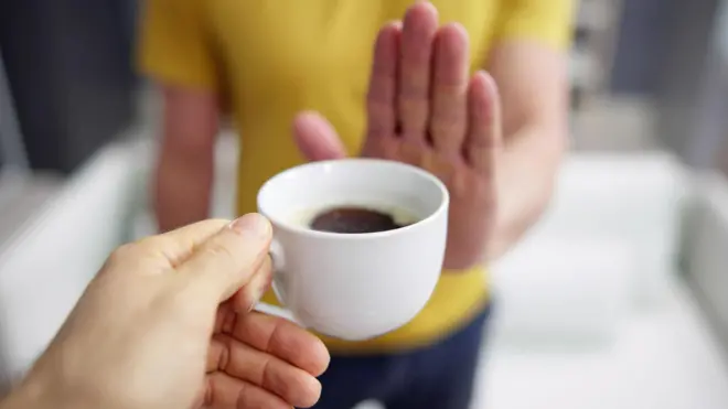 Pessoa oferecendo café enquanto a outra estende a mão em sinal de negação