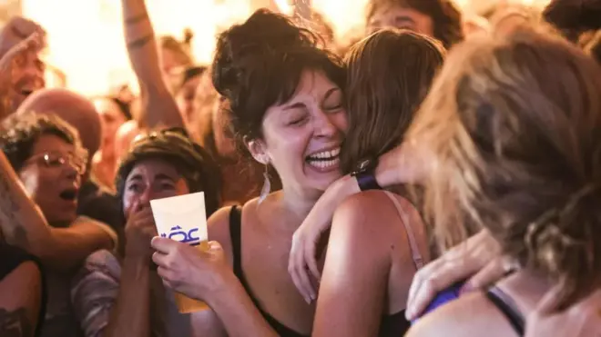 Two young women hug each other in a crowd