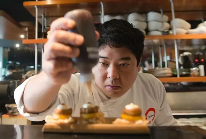 Homem amarelo com roupa de chef montando um prato