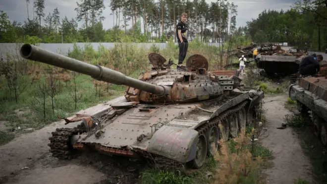 Pessoas inspecionando tanques abandonados em Irpin