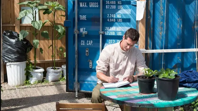 Un hombre toma notas en un cuaderno en un jardín en Gotemburgo.