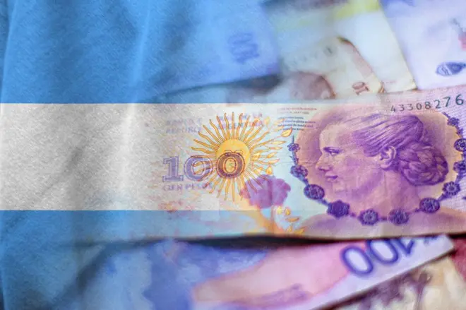 Pesos argentinos em dinheiro e bandeira argentina