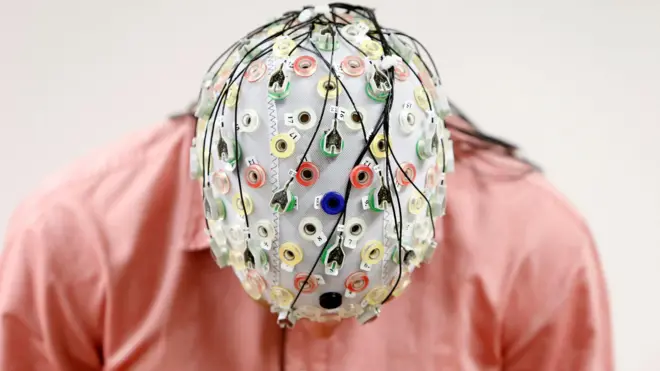 Homem com a cabeça abaixada usa equipamento que mede atividade cerebral