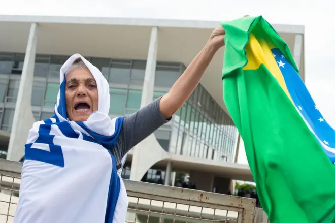 Manifestante enrolada na bandeira de Israel segura uma bandeira do Brasil em frente ao prédio do STF