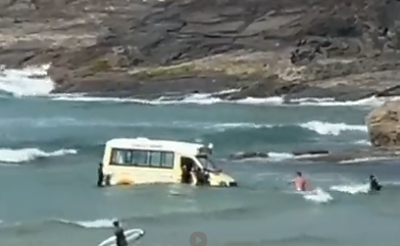 An ice cream van being submerged in water at the beach