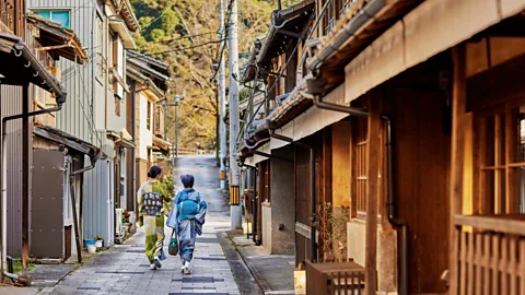 Two people in traditional dress walking through Ozu historic centre