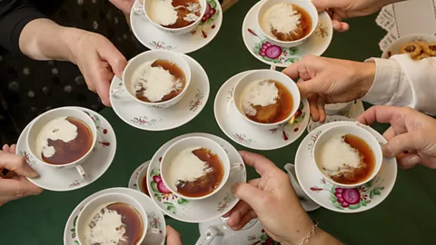 People holding traditional cups and saucers of East Frisian tea (Credit: Bünting Tea Museum)