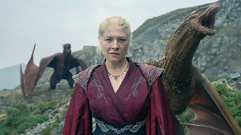 Emma D'arcy as Princess Rhaenyra Targaryen in House of the Dragon, stood in front of two dragons (Credit: Theo Whiteman/ HBO)