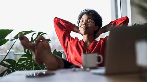 Alamy woman reclined in office with feet on desk (Credit: Alamy)