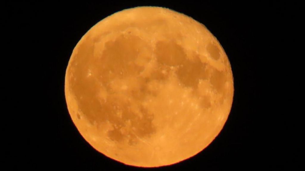 Full orange moon with dark patches