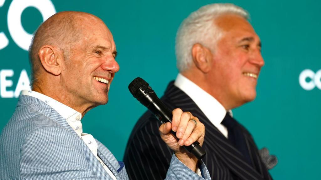 Adrian Newey holds a microphone while sat next to Lawrence Stroll 