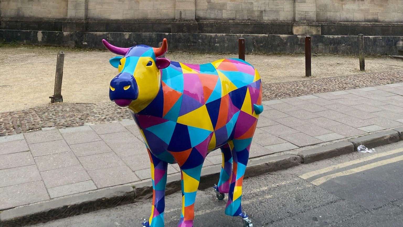 An ox sculpture which is multi-coloured and in the road