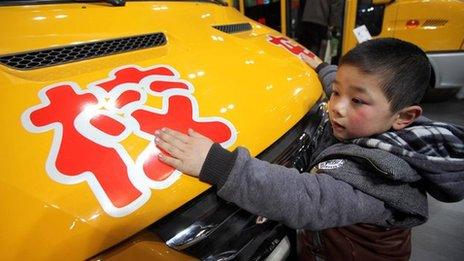 A young boy takes a close look at a new school bus at the International School Bus Exhibition in Beijing, 15 February 2012