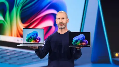 Microsoft Corporate Vice President, Surface Devices Brett Ostrum holds laptops during a presentation at Microsoft's May 20 briefing. event at Microsoft in Redmond, Washington, on May 20, 2024. Microsoft unveiled a new category of PC on Monday that features generative artificial intelligence tools built directly into Windows, the company's world leading operating system.