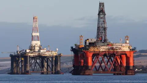 An oil platform standing amongst other rigs that have been left in the Cromarty Firth near Invergordon in the Highlands of Scotland.