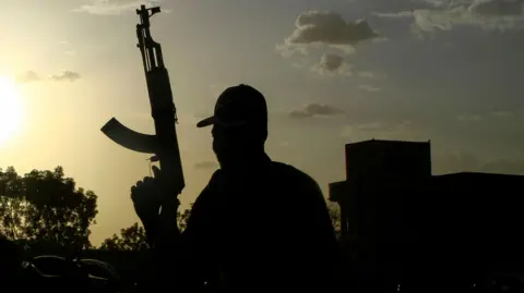 AFP A silhouetted Sudanese fighter holds up a gun