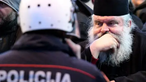 AFP Serbian Orthodox Church clergy and believers stand in front of police near the parliament on 26 December