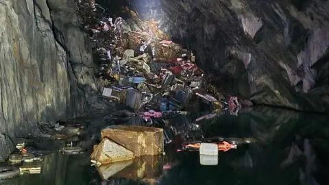 The pile of rusting cars and scrap metal in the quarry