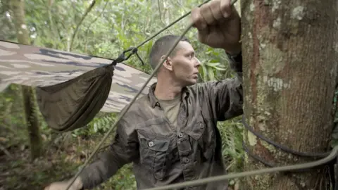 A legionnaire erects his hammock in the forest