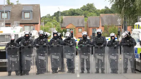 PA Media Riot police form a line after people taking part in an anti-Islamic protest make their way through the area following a protest outside Belfast City Hall