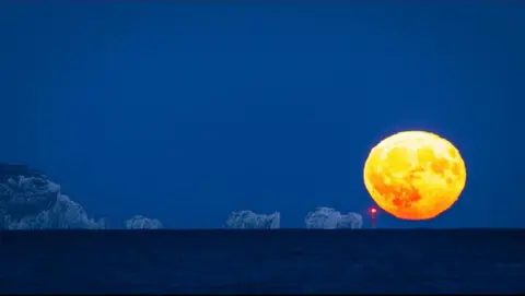 Tim Rosier Photography The size of the moon is really highlighted in this photo by Tim Rosier Photography as it appears to balance on The Needles lighthouse