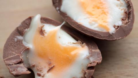 Cadbury's Creme Egg cut in half on a wooden table