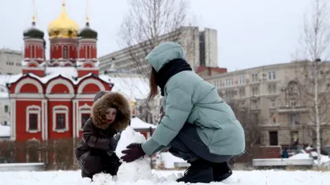 Getty Images Russian child plays in park with his mother in Moscow (9 January)