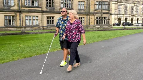 Daren Smith and Debbie Ramsey walking together, with Mr Smith carrying a white stick