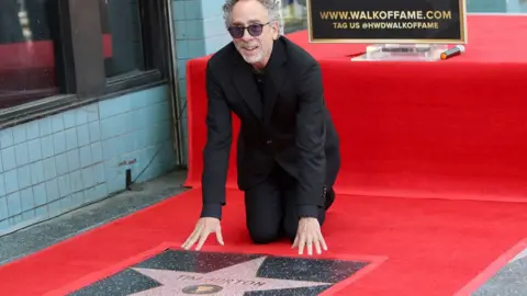 Tim Burton kneels next to his star during a ceremony as he is honored with a star on the Hollywood Walk of Fame in Los Angeles, California, USA, 03 September 2024