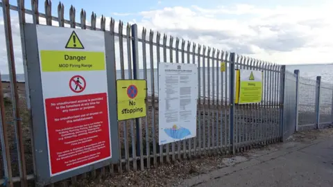 HM Coastguard Southend On Sea Warning signs on a boundary fence around MOD Shoeburyness